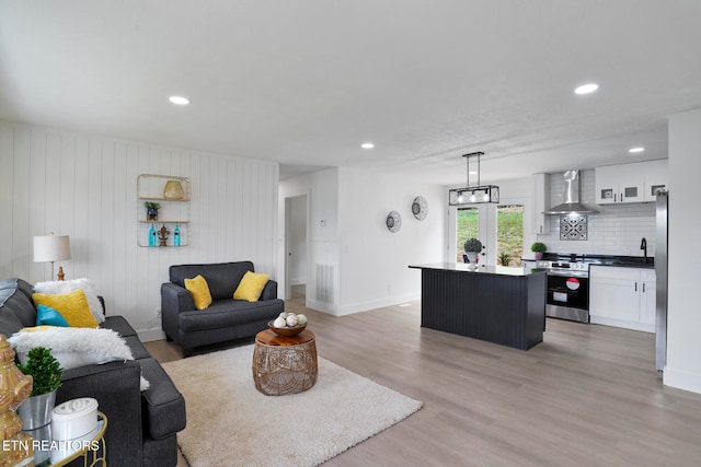 living room with light hardwood / wood-style flooring and wooden walls