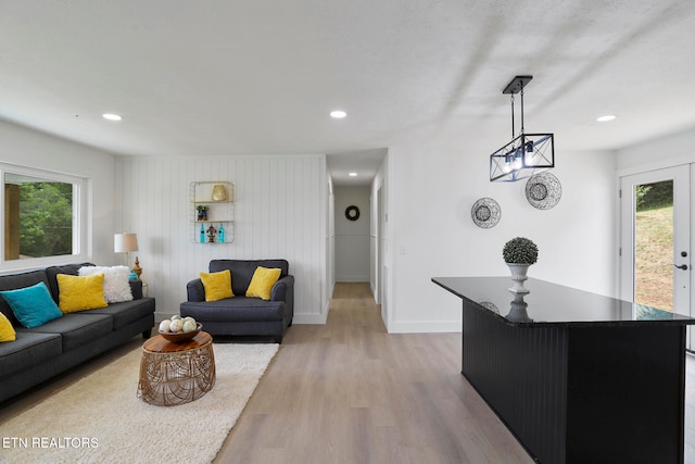 living room with wooden walls, light hardwood / wood-style floors, a wealth of natural light, and french doors