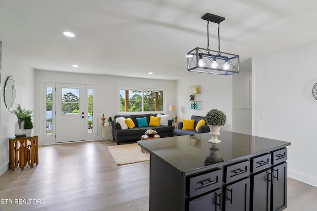 kitchen with decorative light fixtures, a center island, dark stone countertops, and light wood-type flooring