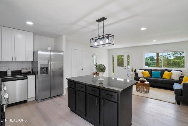 kitchen featuring hanging light fixtures, light wood-type flooring, appliances with stainless steel finishes, a kitchen island, and white cabinetry