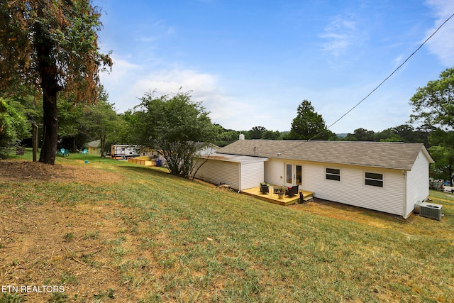 rear view of house with a yard, a wooden deck, and central AC