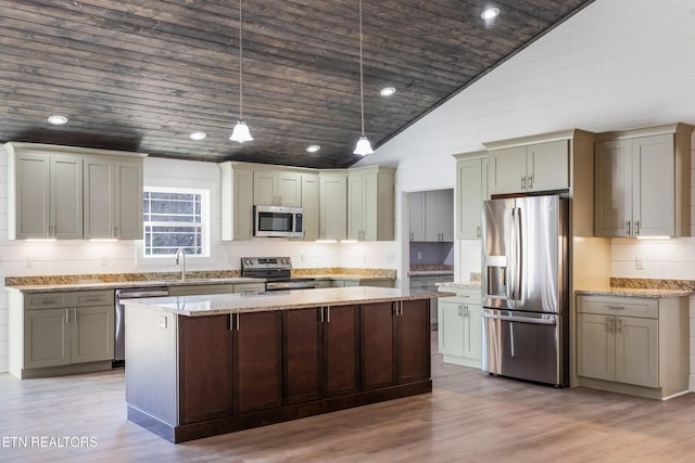 kitchen with appliances with stainless steel finishes, pendant lighting, sink, light stone counters, and light wood-type flooring