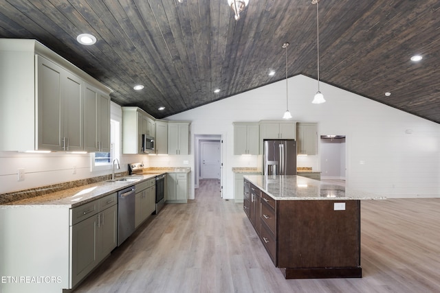 kitchen with sink, hanging light fixtures, stainless steel appliances, light stone counters, and a kitchen island