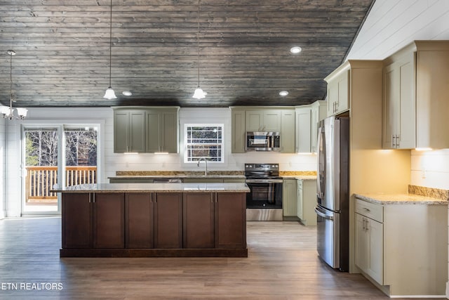 kitchen featuring stainless steel appliances, hanging light fixtures, light stone counters, and light wood-type flooring