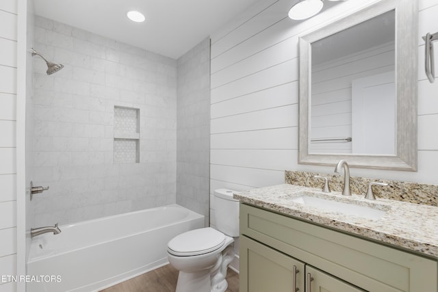 full bathroom with tiled shower / bath, vanity, toilet, and hardwood / wood-style floors