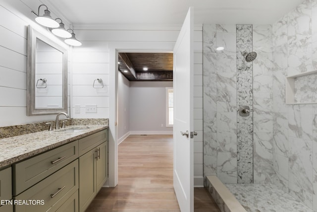 bathroom with hardwood / wood-style flooring, vanity, ornamental molding, and a tile shower