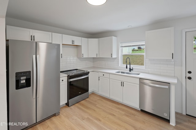 kitchen with sink, white cabinets, stainless steel appliances, and light hardwood / wood-style floors