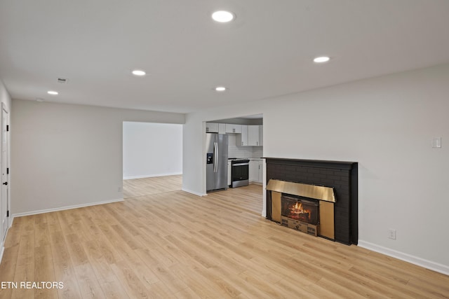 unfurnished living room featuring a fireplace and light hardwood / wood-style flooring