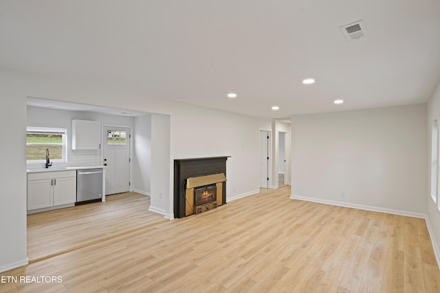 unfurnished living room with light hardwood / wood-style flooring and sink