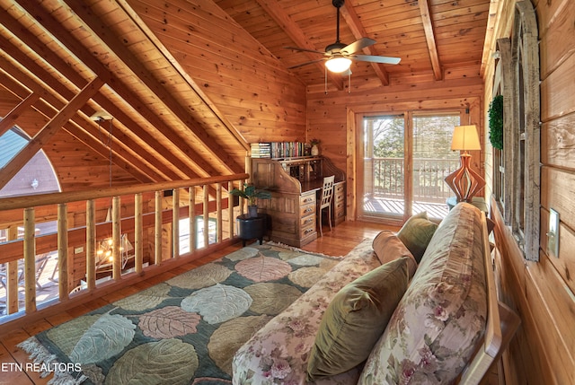 unfurnished room featuring vaulted ceiling with beams, light hardwood / wood-style floors, ceiling fan, and wood walls