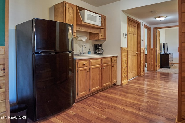 kitchen with hardwood / wood-style flooring, black fridge, and sink