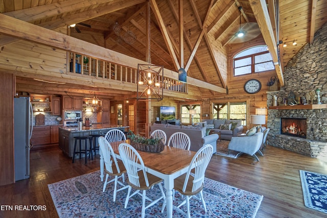 dining area with wood walls, wooden ceiling, high vaulted ceiling, a fireplace, and dark hardwood / wood-style flooring