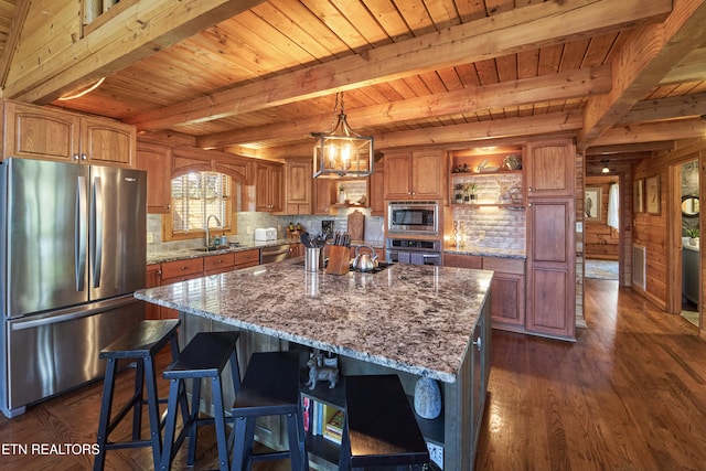 kitchen with dark wood-type flooring, sink, wooden walls, a kitchen island, and stainless steel appliances