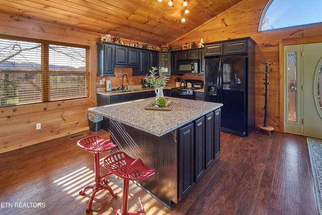 kitchen featuring wood ceiling, vaulted ceiling, black appliances, a center island, and wood walls