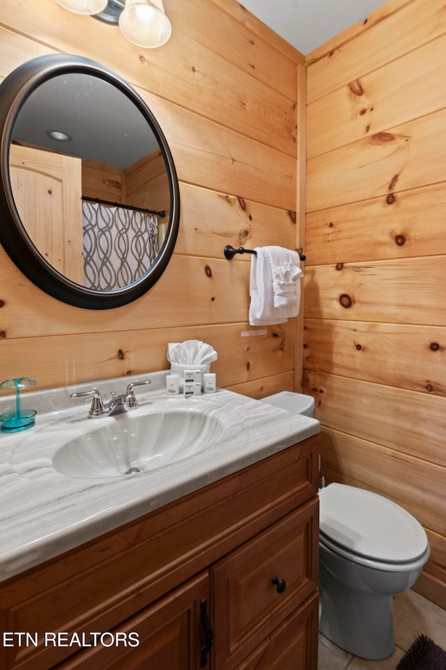 bathroom featuring wood walls, toilet, tile patterned floors, and vanity