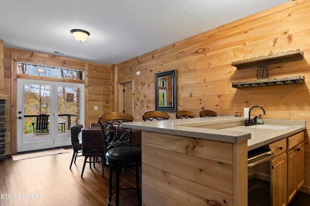 bar with dark wood-type flooring, sink, light stone countertops, and wooden walls