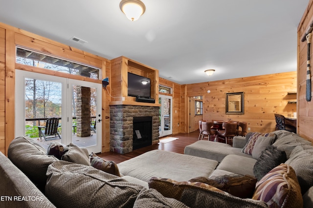 living room featuring wood walls, dark wood-type flooring, and a fireplace