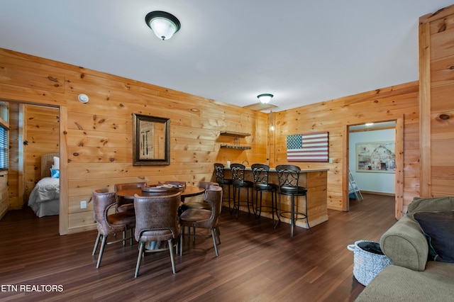 dining area with dark wood-type flooring, wooden walls, and bar area