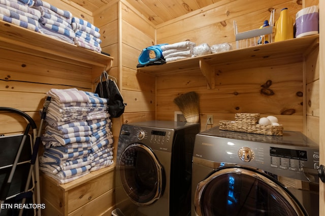 laundry room featuring wood walls and separate washer and dryer