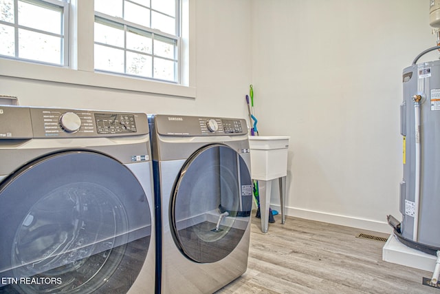 laundry room with washer and dryer, hardwood / wood-style floors, and electric water heater