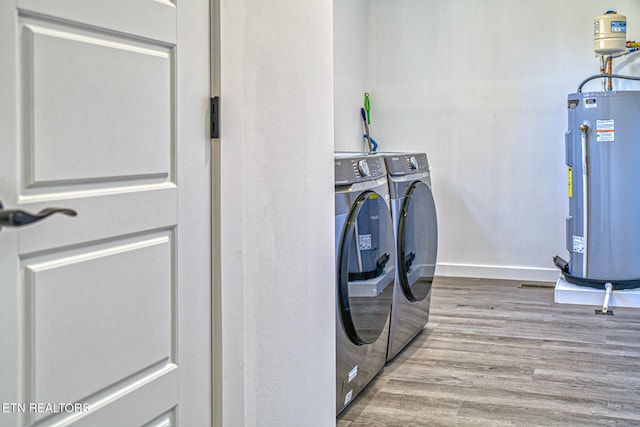 laundry area featuring electric water heater, hardwood / wood-style flooring, and washer and clothes dryer