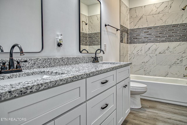 full bathroom featuring hardwood / wood-style floors, vanity, toilet, and tiled shower / bath combo