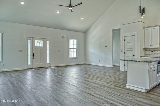 unfurnished living room featuring ceiling fan, light wood-type flooring, and high vaulted ceiling