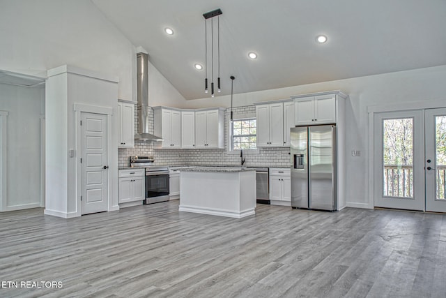 kitchen featuring appliances with stainless steel finishes, decorative light fixtures, high vaulted ceiling, light hardwood / wood-style floors, and white cabinetry