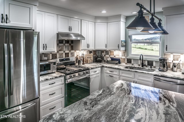 kitchen with appliances with stainless steel finishes, decorative light fixtures, white cabinetry, and sink