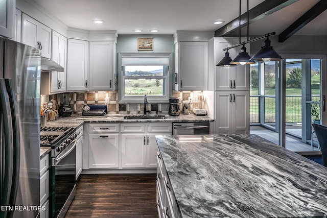 kitchen with decorative backsplash, stainless steel appliances, sink, stone countertops, and white cabinets