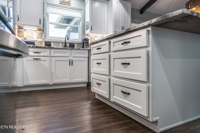 kitchen with beamed ceiling, white cabinets, dark stone counters, and dark hardwood / wood-style floors