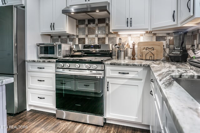 kitchen with light stone countertops, white cabinetry, stainless steel appliances, and dark hardwood / wood-style floors