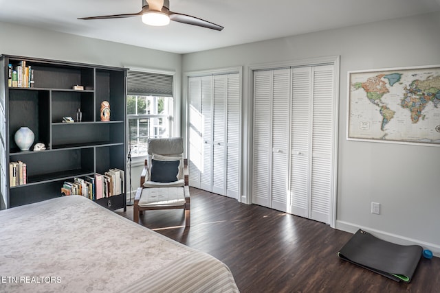 bedroom with two closets, ceiling fan, and dark wood-type flooring