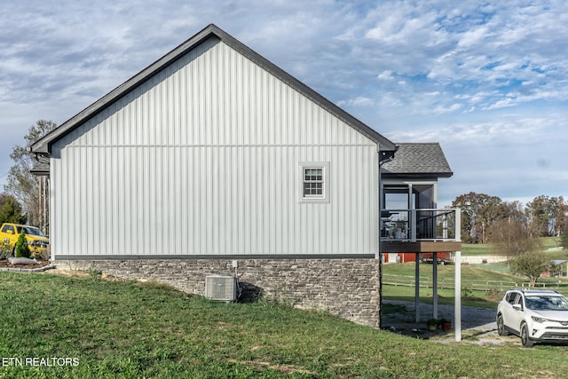 view of side of home featuring a lawn and central AC