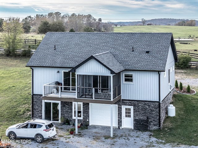 back of house featuring a rural view, a garage, and a sunroom