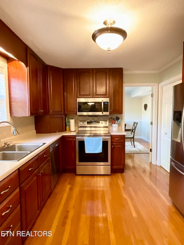 kitchen with a sink, light countertops, light wood-style flooring, and stainless steel appliances