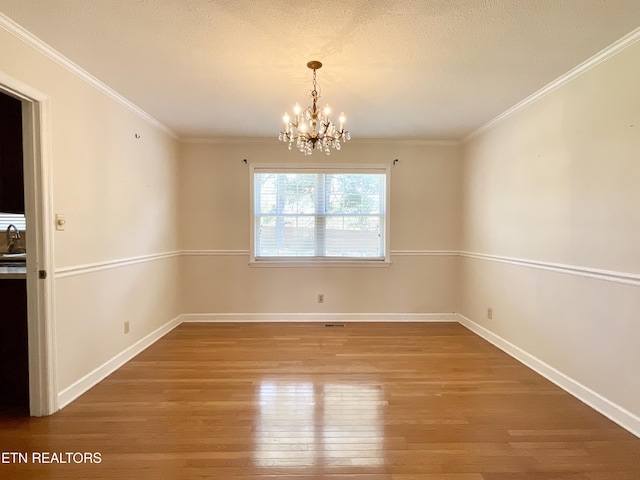 unfurnished dining area featuring baseboards, a notable chandelier, wood finished floors, and ornamental molding