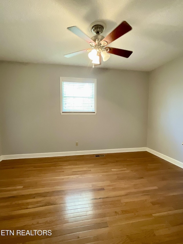 unfurnished room featuring visible vents, wood finished floors, baseboards, and ceiling fan