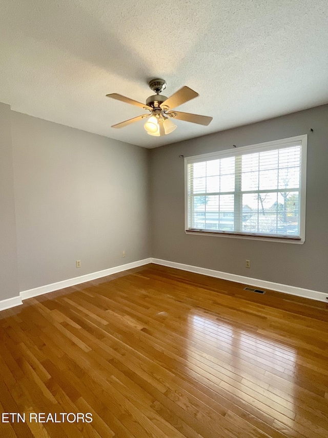 spare room featuring a wealth of natural light, visible vents, and hardwood / wood-style floors