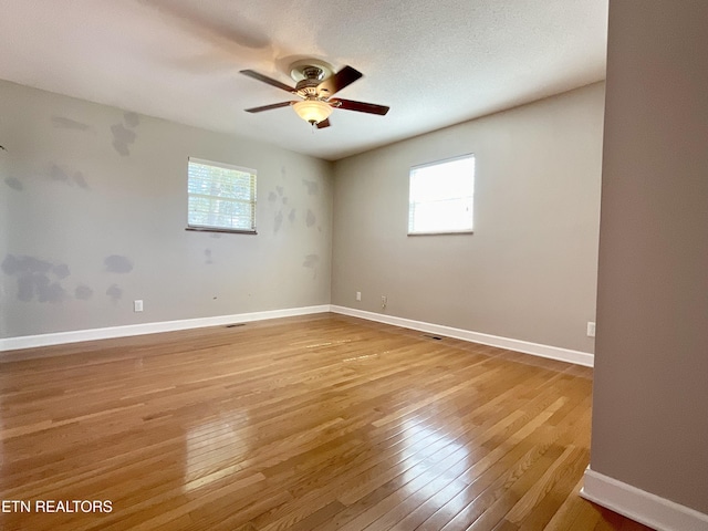 spare room featuring plenty of natural light, baseboards, light wood finished floors, and ceiling fan