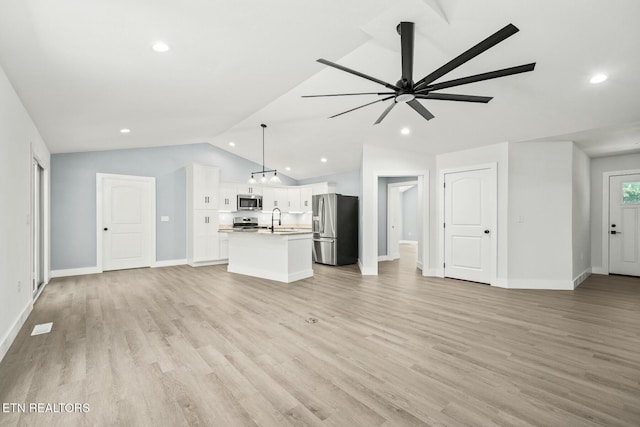 unfurnished living room with light wood-type flooring, vaulted ceiling, ceiling fan, and sink