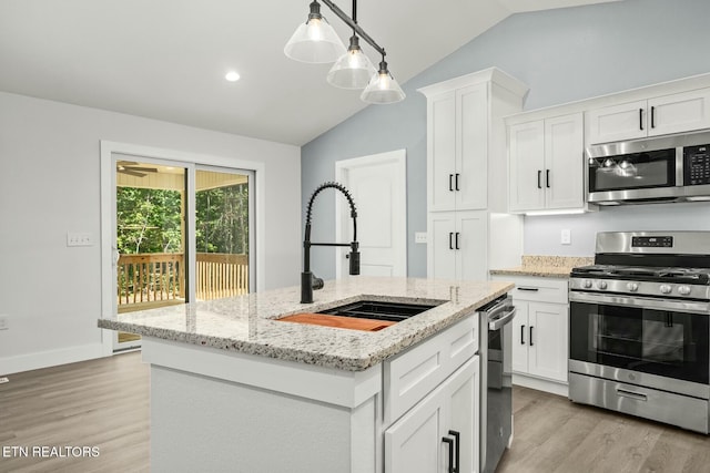 kitchen with stainless steel appliances, white cabinetry, a center island with sink, and sink