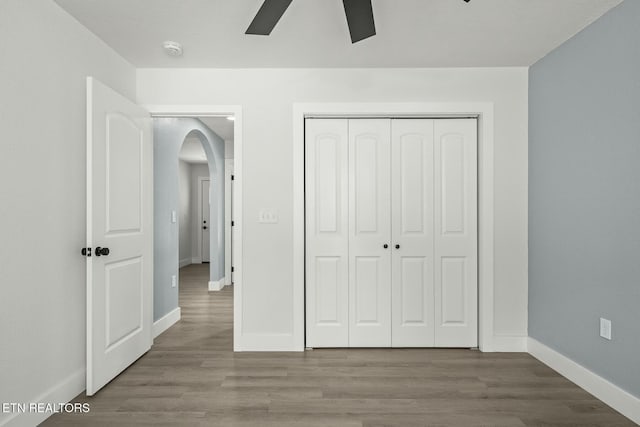 unfurnished bedroom with wood-type flooring, a closet, and ceiling fan