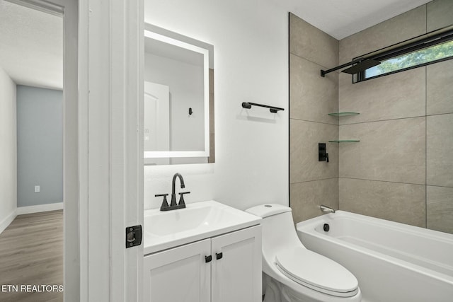 full bathroom with wood-type flooring, a textured ceiling, toilet, vanity, and tiled shower / bath