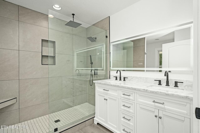 bathroom featuring tiled shower and vanity