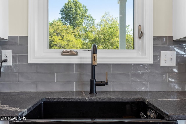 details with backsplash, white cabinetry, and sink