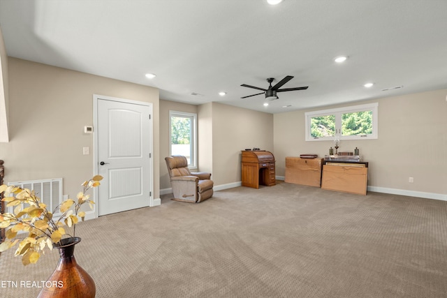 living area with ceiling fan, a healthy amount of sunlight, and light colored carpet