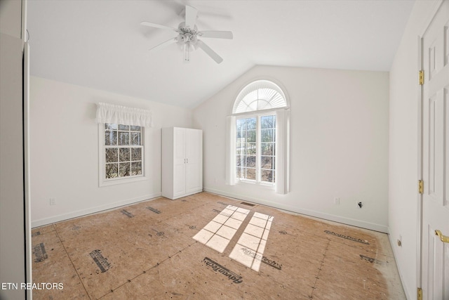 unfurnished room with vaulted ceiling, baseboards, and ceiling fan