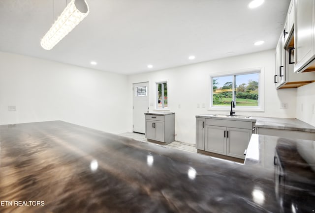 interior space with gray cabinets, sink, and pendant lighting