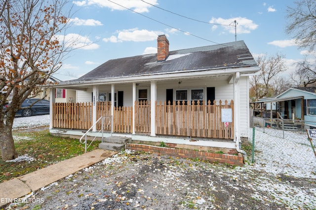 snow covered house featuring covered porch